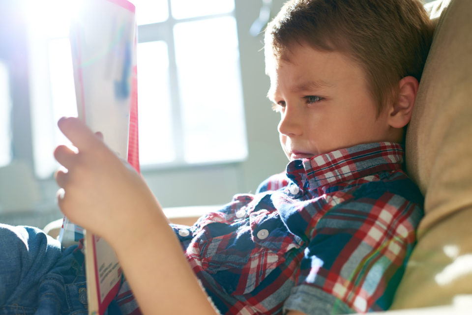 Side view of relaxing boy reading magazine