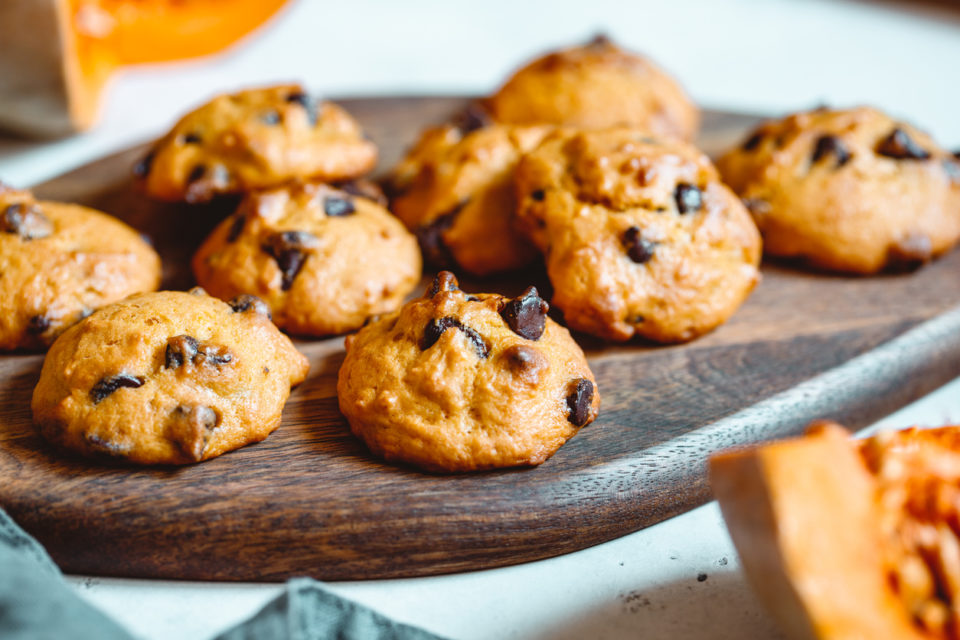 Pumpkin cookies with chocolate chips made from cake mix on a wooden tray.