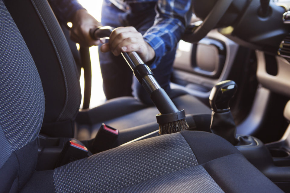 A man vacuuming the front seats of his car