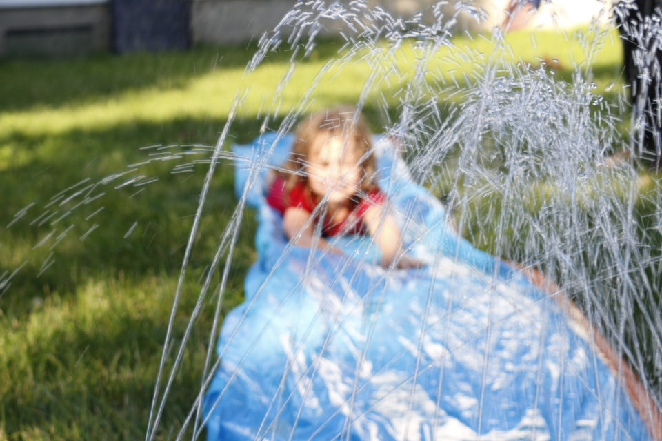 Smiling girl sliding down an outdoor slip and slide