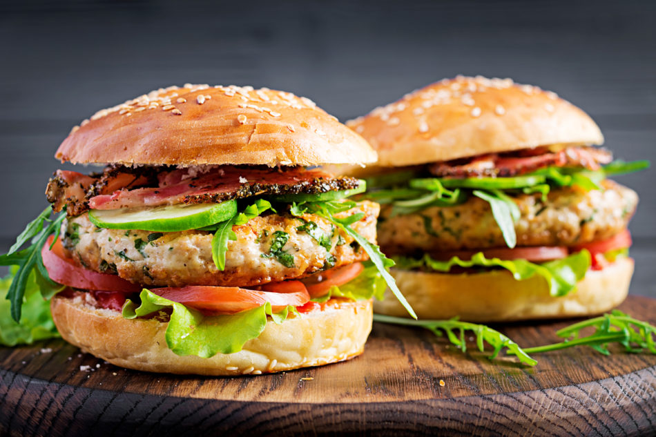 Turkey burgers topped with lettuce, tomatoes, and bacon