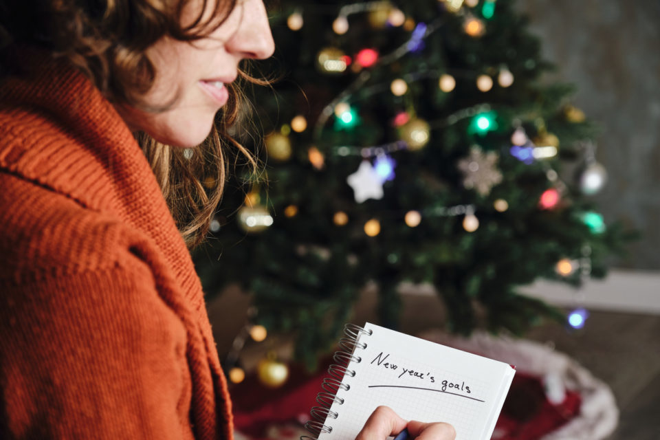 woman smiling with orange sweater in profile with new year's goals