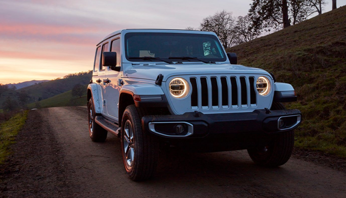 A white 2020 Jeep Wrangler being driven on a country road at sunset