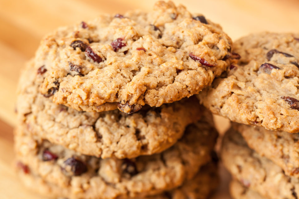 Stack of oatmeal and cranberry cookies on wood surface.