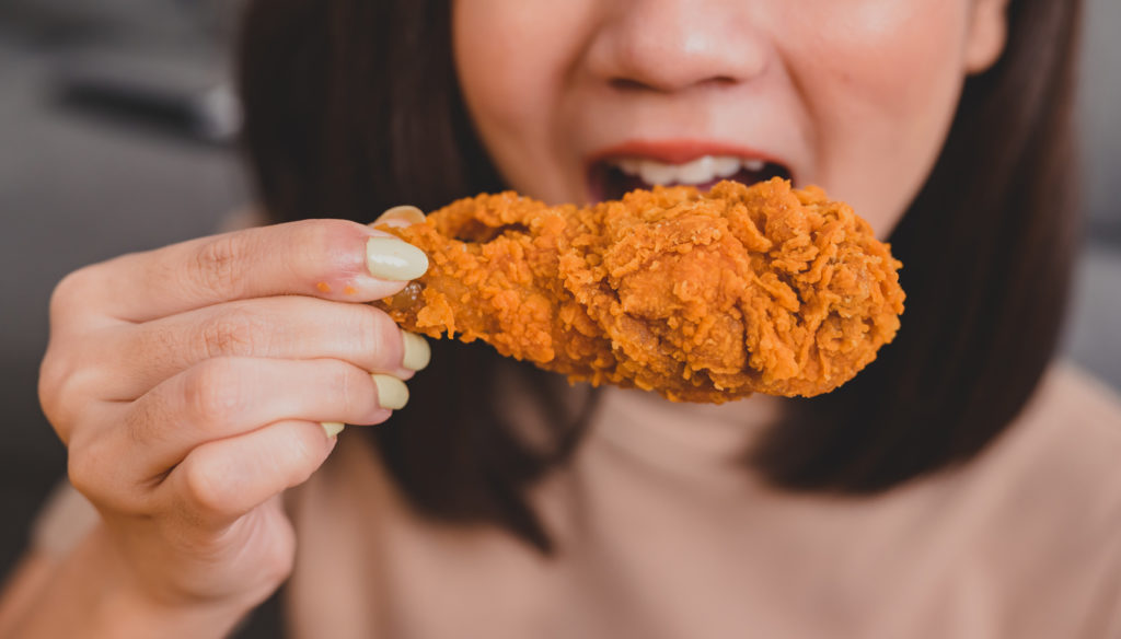 Woman eating a fried chicken finger