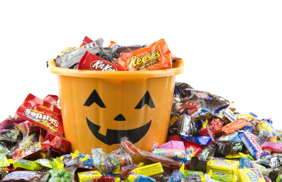 Orange plastic halloween bucket filled and overflowing with candy